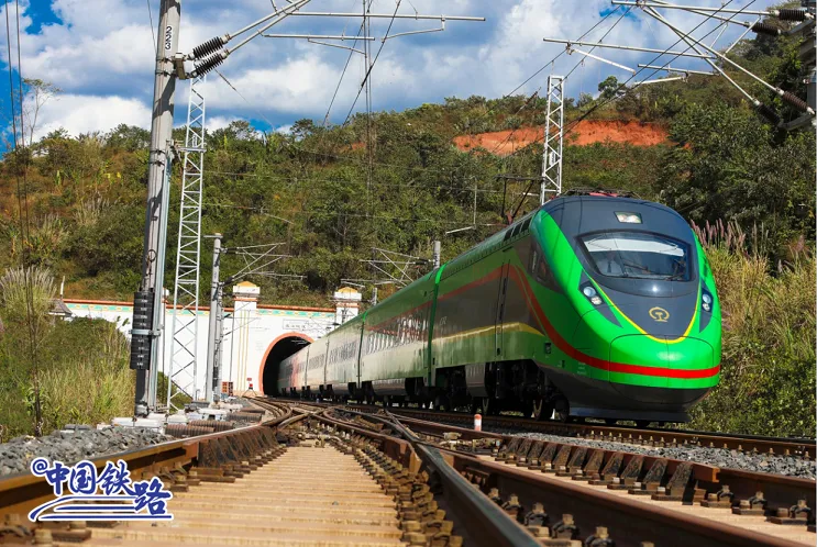 Green Fuxing train emerging from a tunnel