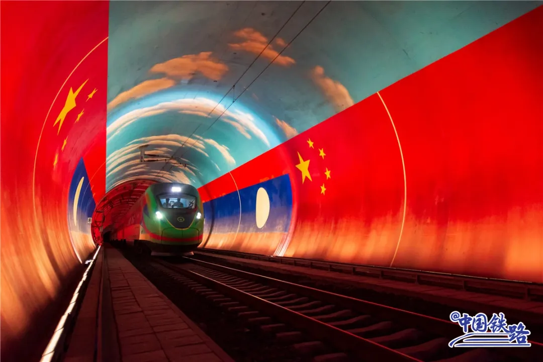 Train at a tunnel entrance decorated with Chinese and Lao flags
